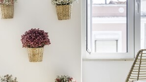 A room with a wooden floor, a round table with two white vases, and a window with a view of buildings. - Tile House 95, Penha de França (Lisboa)