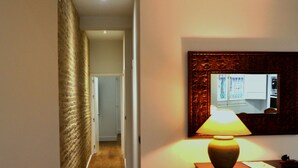 A hallway with wooden flooring, a lamp on a nightstand, and a mirror on the wall. - GREAT APARTMENT IN CASCO ANTIGUO (Sevilla)