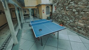 Una mesa de ping pong en un patio con paredes de piedra y suelo de baldosas.