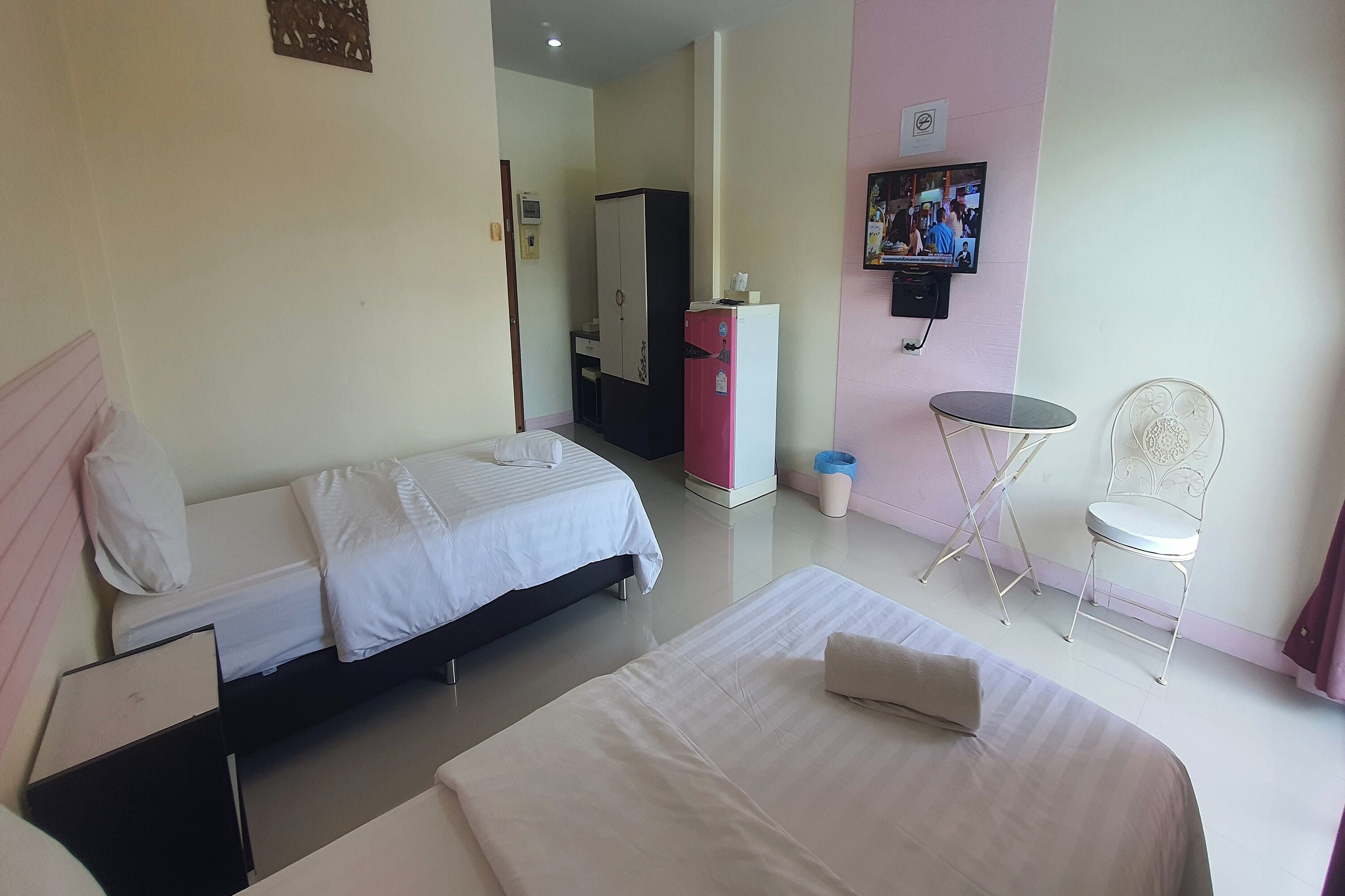 A hotel room with two beds, a desk, a chair, a TV, and a wardrobe.