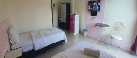 A hotel room with two beds, a desk, a chair, a TV, and a wardrobe.