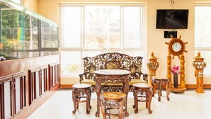 Um quarto com uma janela grande, um banco de madeira, uma mesa e um relógio.