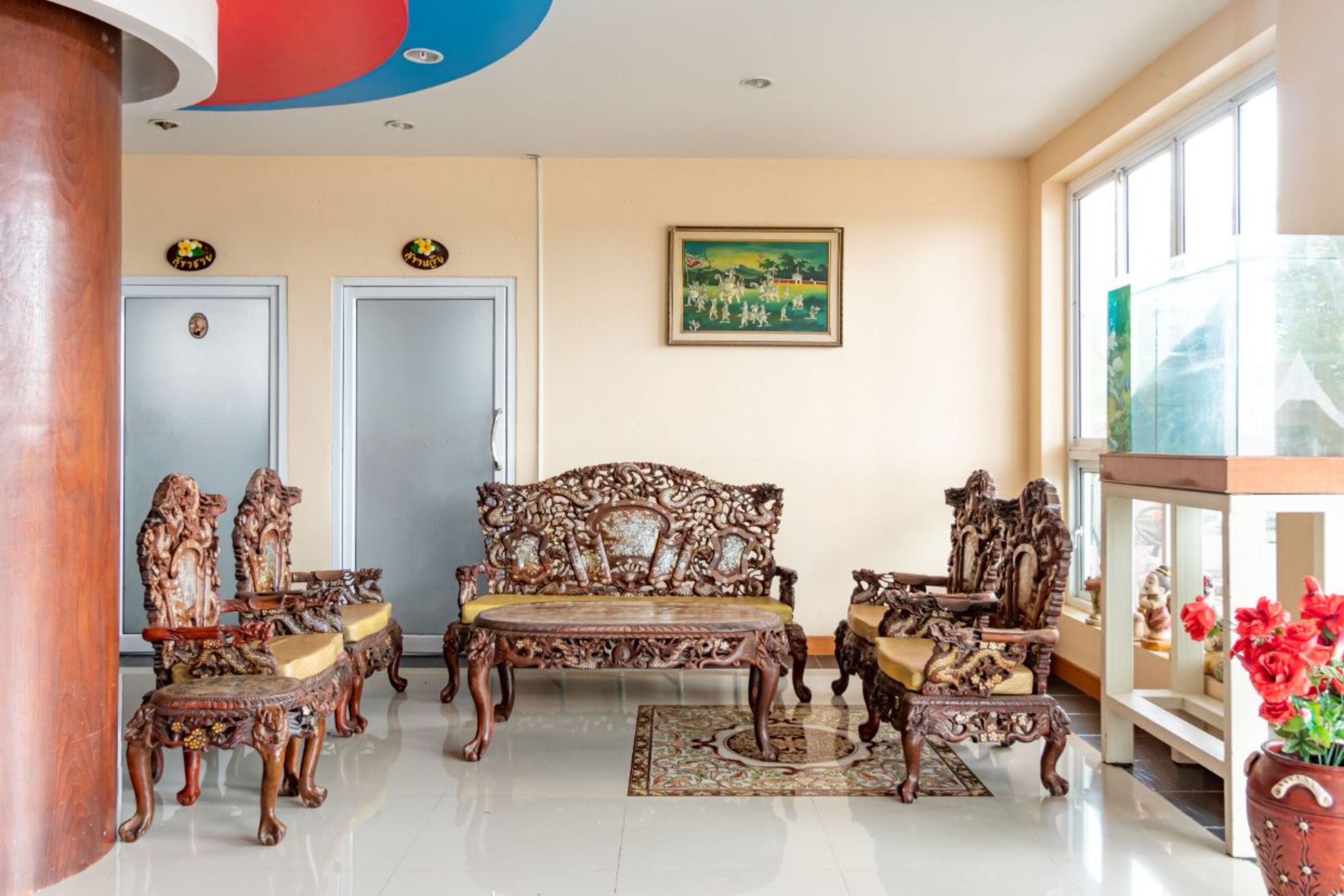 A traditional room with ornate wooden furniture, a large window, and a painting on the wall.