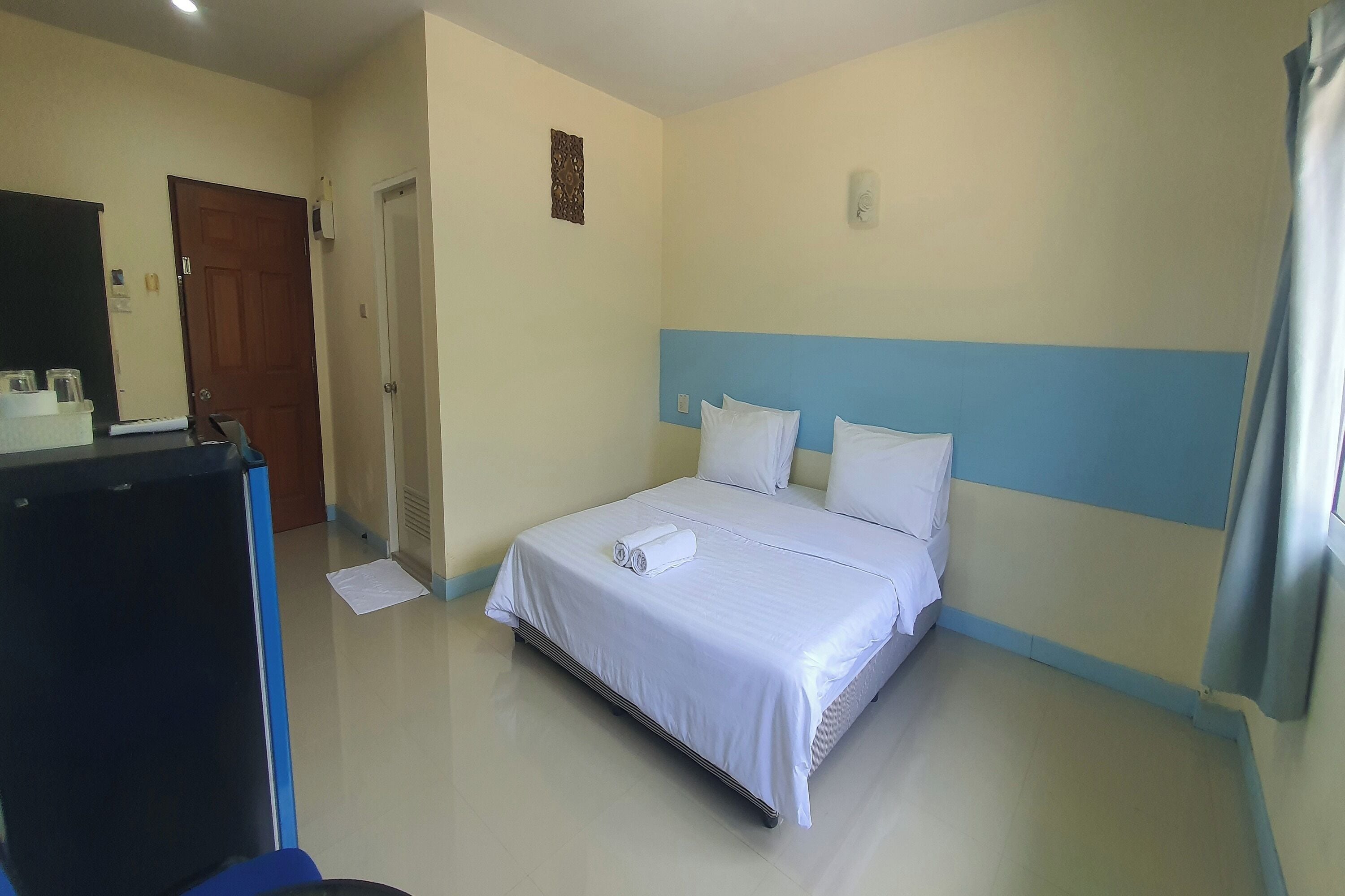 A hotel room with a bed, a desk, and a door.
