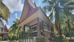 Um edifício em estilo tradicional com telhado inclinado, rodeado por vegetação exuberante e palmeiras.