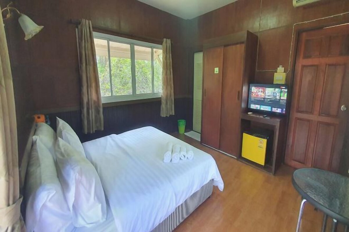 Une chambre d’hôtel avec un lit, une télévision et une armoire.