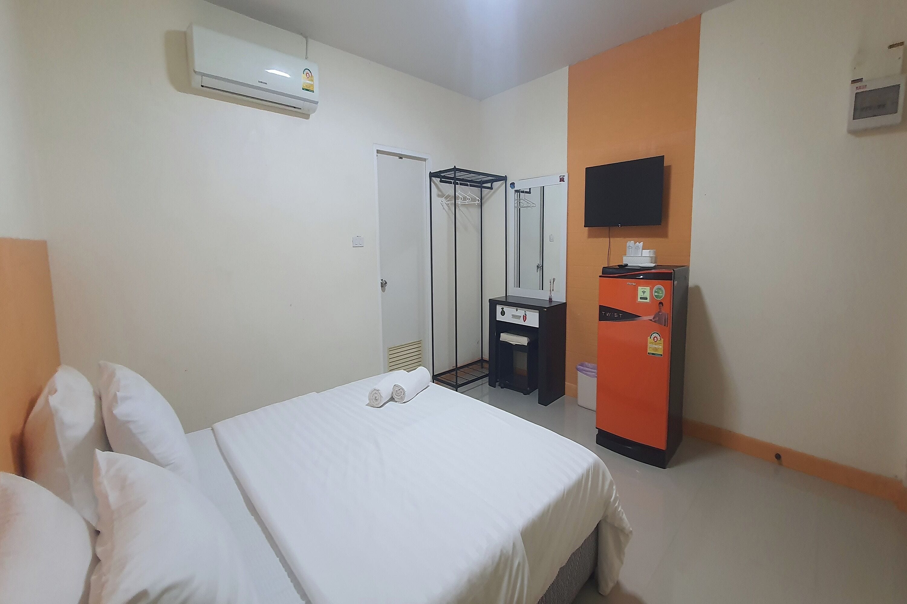 Habitación de hotel con cama, armario, espejo, televisor y minibar.