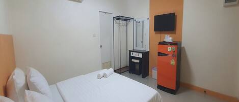Habitación de hotel con cama, armario, espejo, televisor y minibar.