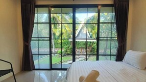 Quarto com uma grande janela, cama e um banco.