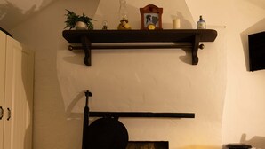 Une pièce chaleureuse avec une cheminée, une étagère au-dessus et une petite table ornée de bougies.