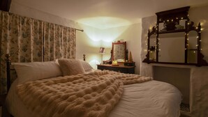 Une chambre avec un grand lit, une table de chevet, une commode, un miroir et des guirlandes lumineuses.