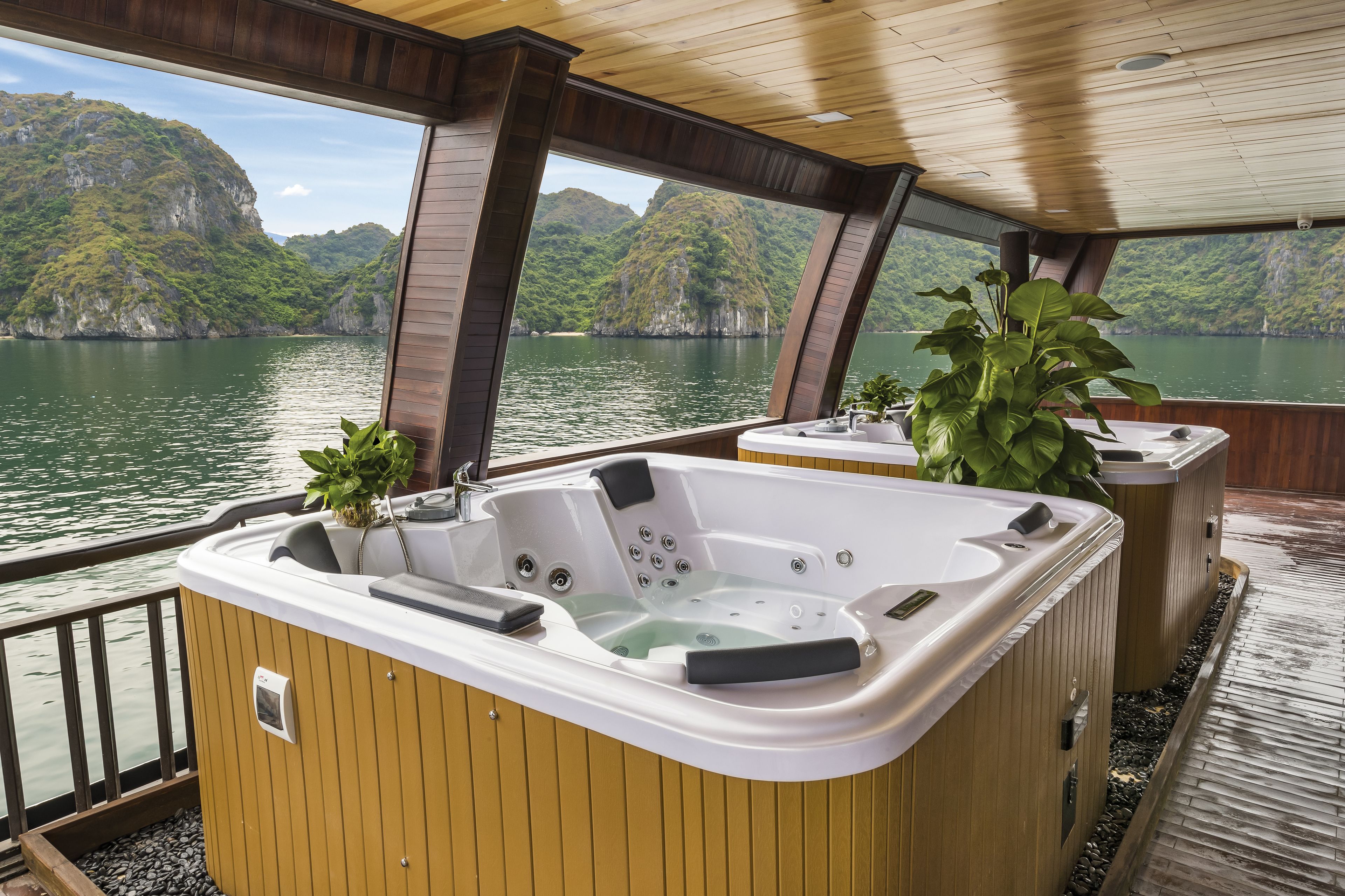 A hot tub with a wooden deck and a view of a mountainous lake.