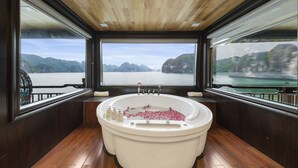 A large bathtub with a view of a body of water and mountains. - La Regina Legend Cruise (Tuan Chau)