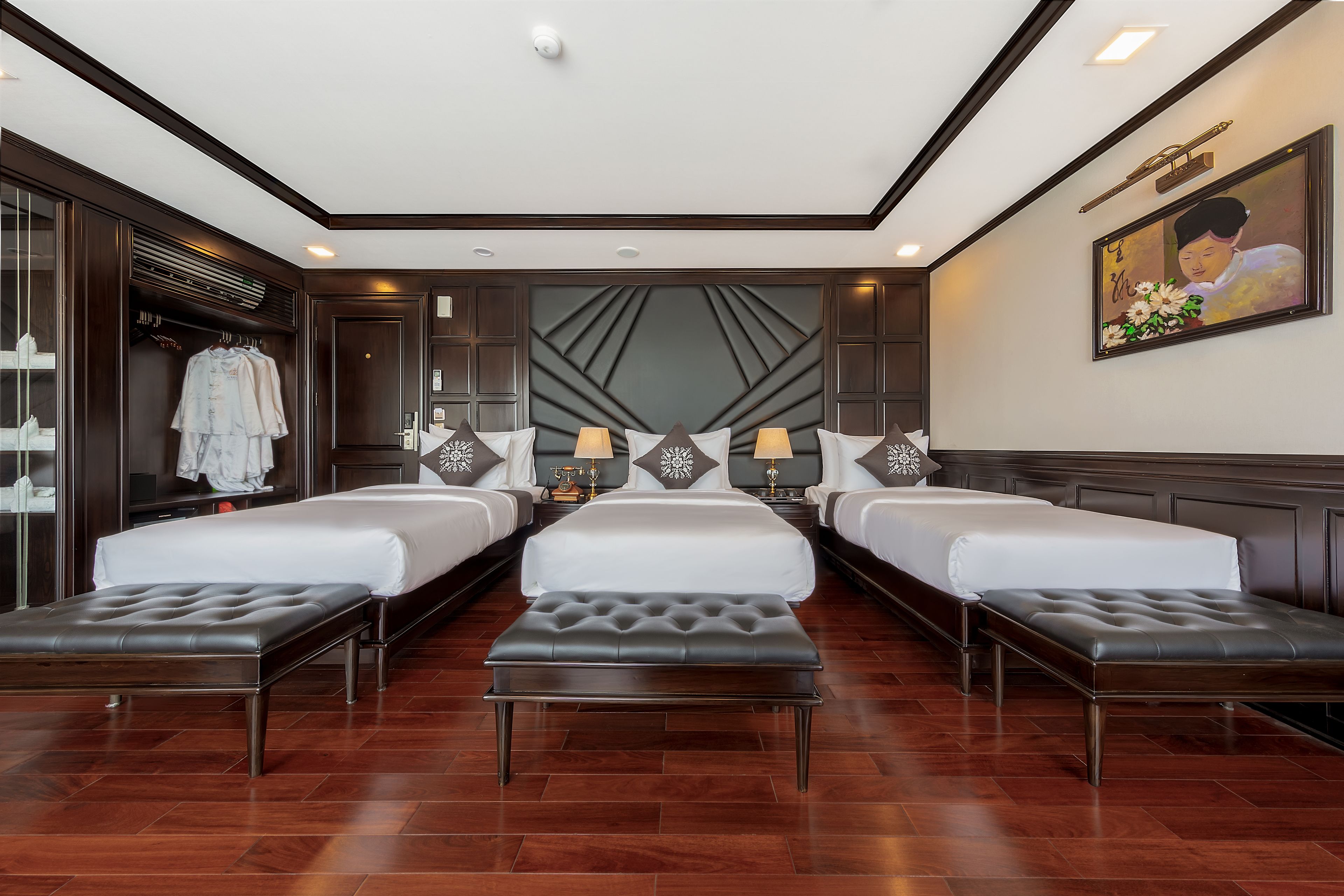 Une chambre d’hôtel avec trois lits, un grand miroir et un panneau décoratif mural.