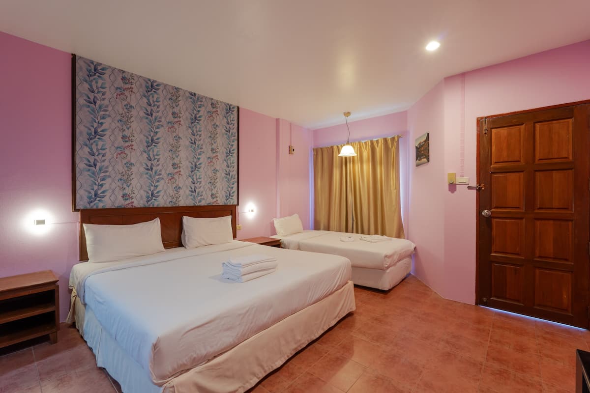 Une chambre d’hôtel avec deux lits, une porte en bois et un papier peint à motifs floraux.