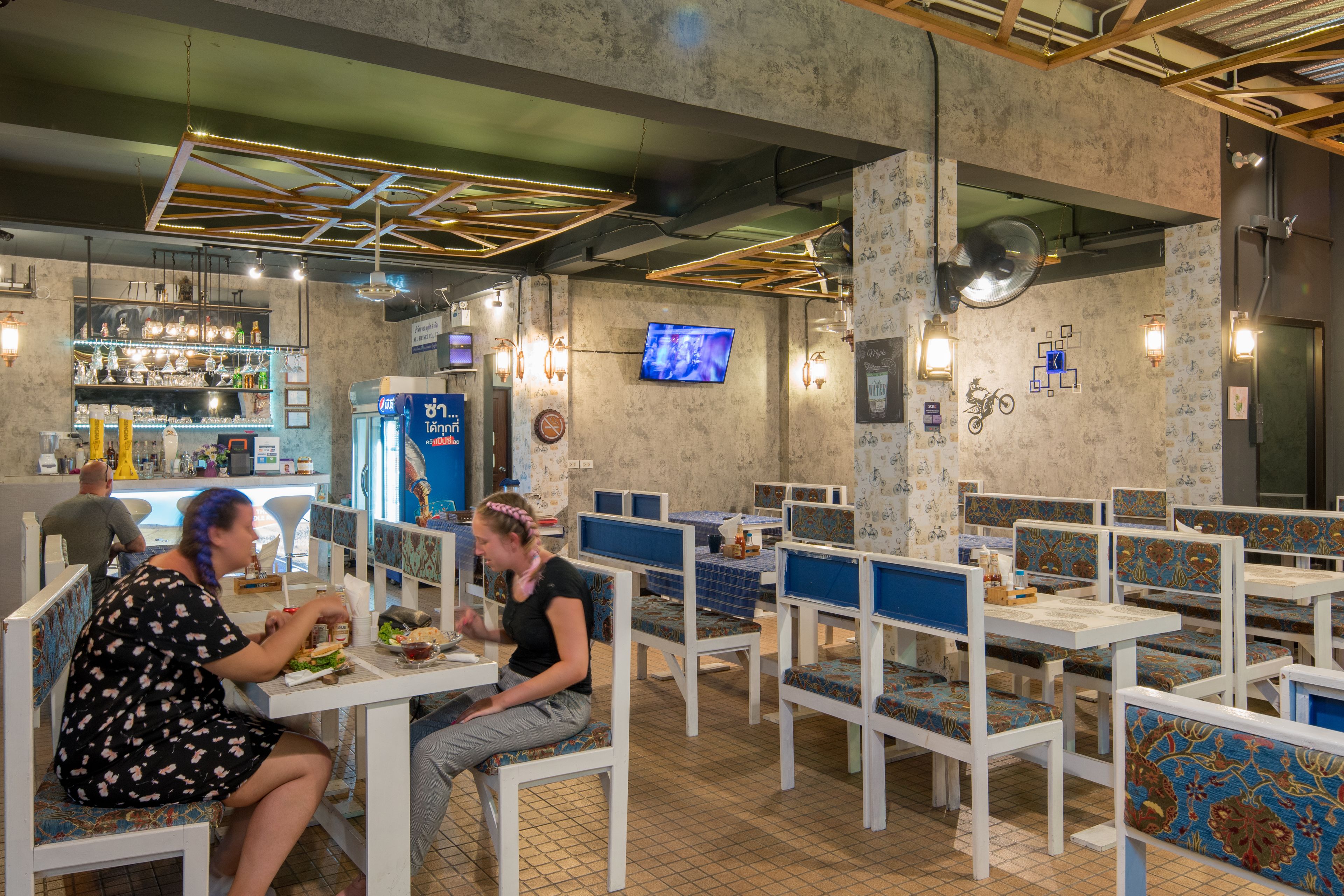 A restaurant with booths and tables, a bar area, and a television screen.