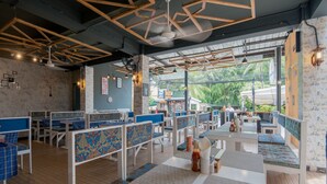 Um restaurante com cabines e mesas, apresentando um design moderno no teto e vista para áreas verdes lá fora.