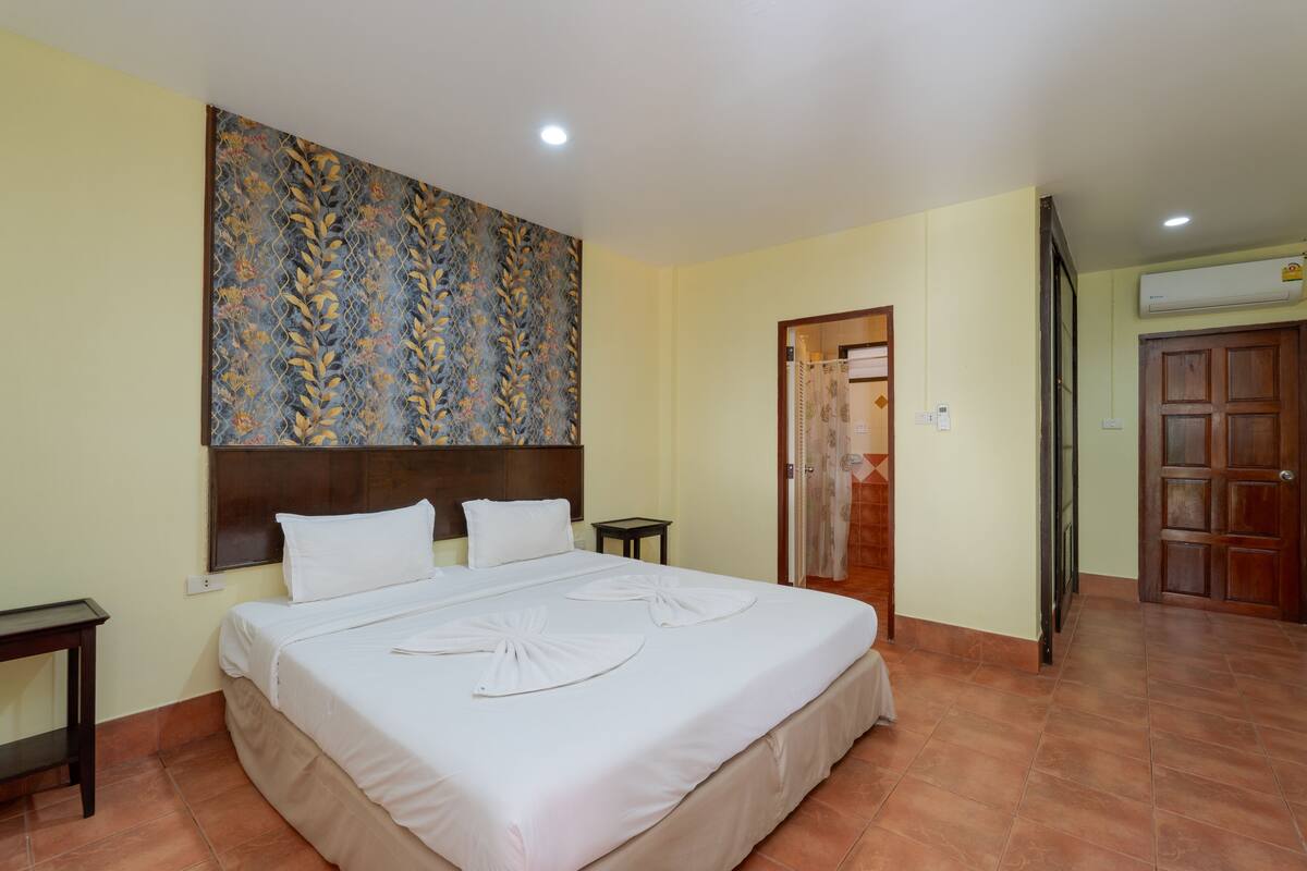 Une chambre d’hôtel avec un grand lit, une tête de lit, une table de chevet, une armoire et un appareil de climatisation.