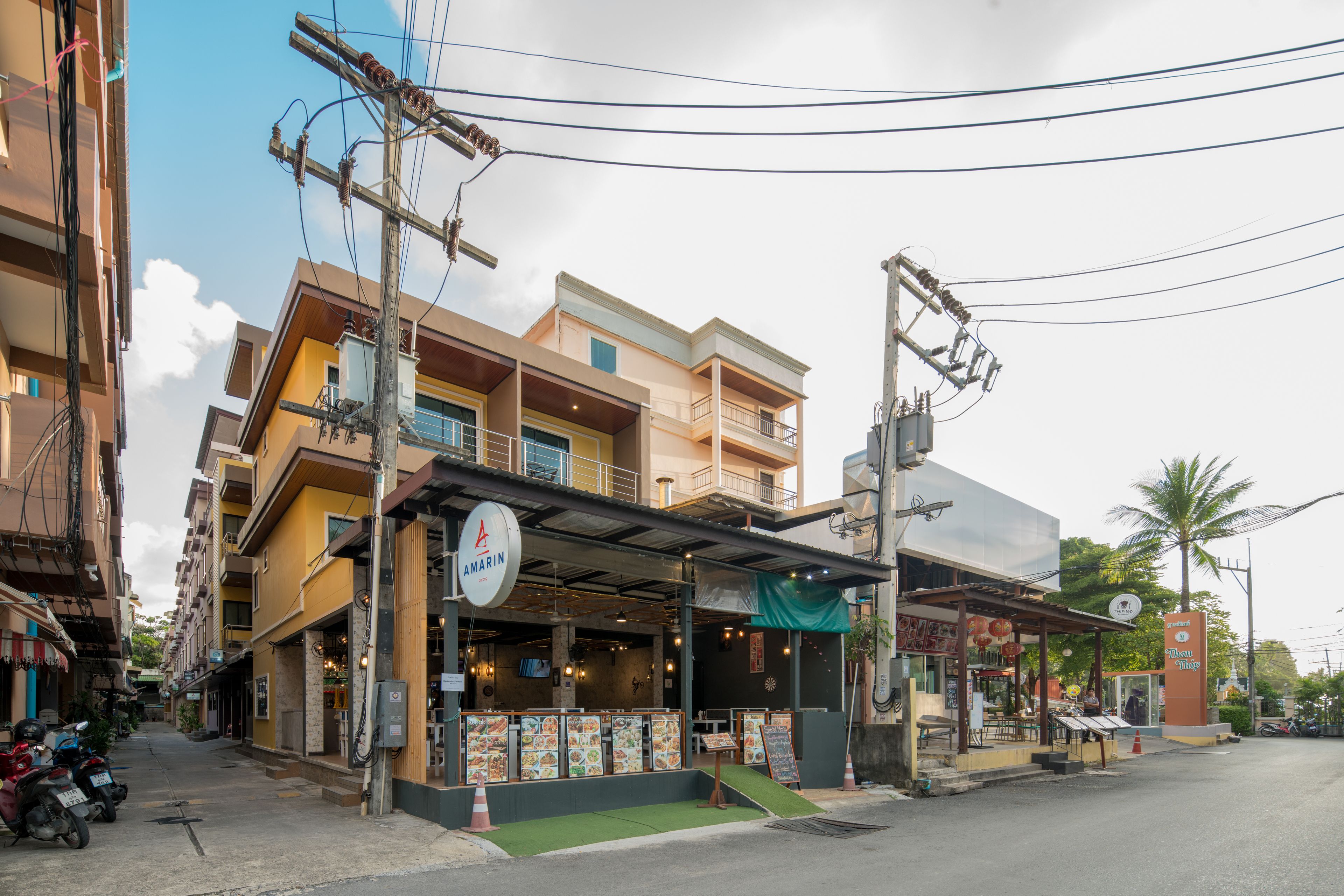 A restaurant with outdoor seating, a signboard, and a green awning.