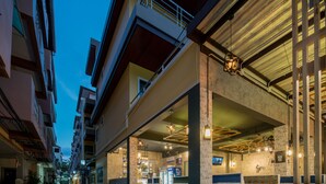 Um edifício com vários andares, varandas, área de estar coberta ao ar livre e um bar visível.