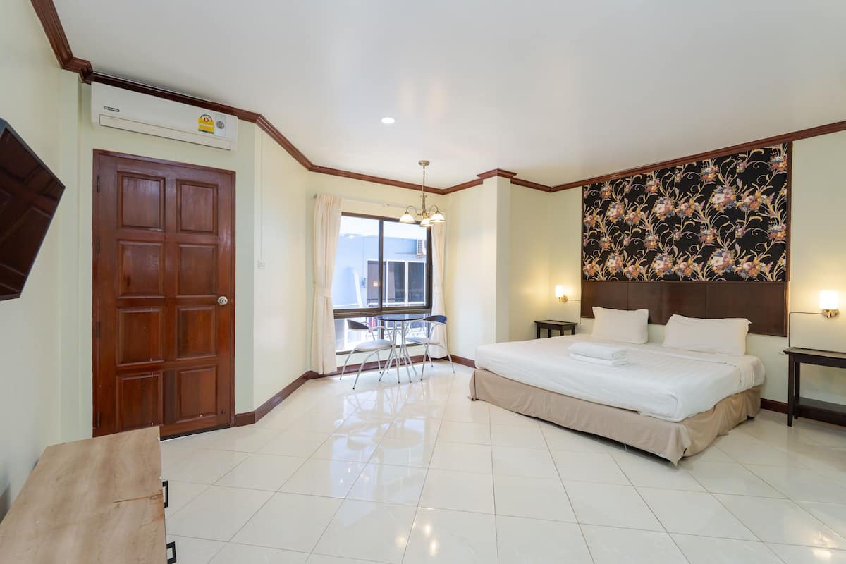Une chambre d’hôtel avec un grand lit, un bureau et une fenêtre avec des rideaux.