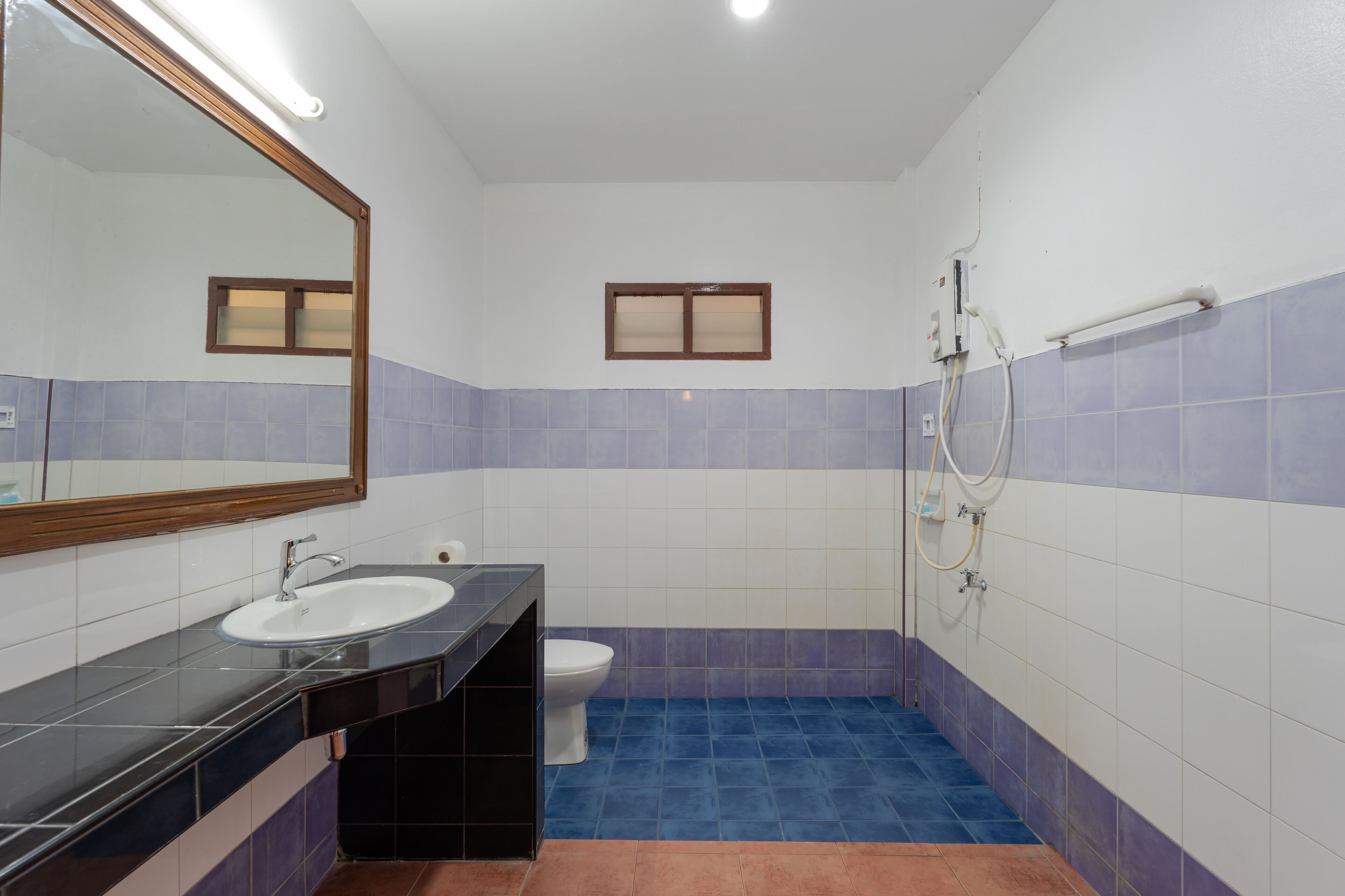 A bathroom with a sink, mirror, toilet, and shower.