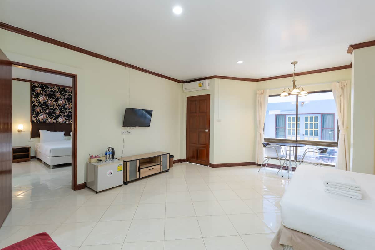 Une chambre d’hôtel comprenant un lit, une télévision, un petit bureau avec une chaise, une fenêtre avec des rideaux et une porte.