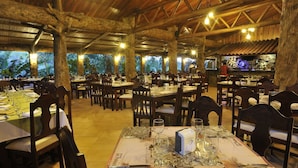An outdoor restaurant with multiple tables and chairs, set against a backdrop of trees and a clear sky. - Los lagos (La Fortuna)