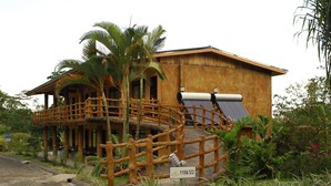 A wooden building with a balcony, surrounded by tropical plants. - Los lagos (La Fortuna)