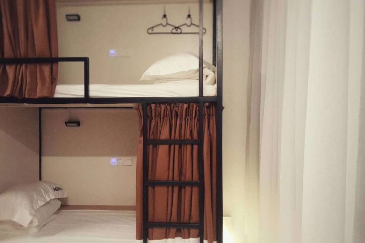 A bunk bed room with a ladder, a white pillow, and a wall-mounted hanger.