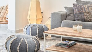 Un salon moderne avec un canapé gris, une table basse en bois et deux poufs ronds.