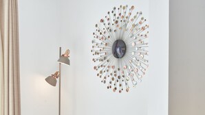 Un salon moderne agrémenté d’un élément décoratif mural rond, d’un lampadaire et d’un pouf en osier.