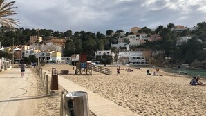 Une plage avec une promenade en bois, des bâtiments en arrière-plan et un panneau indicateur.