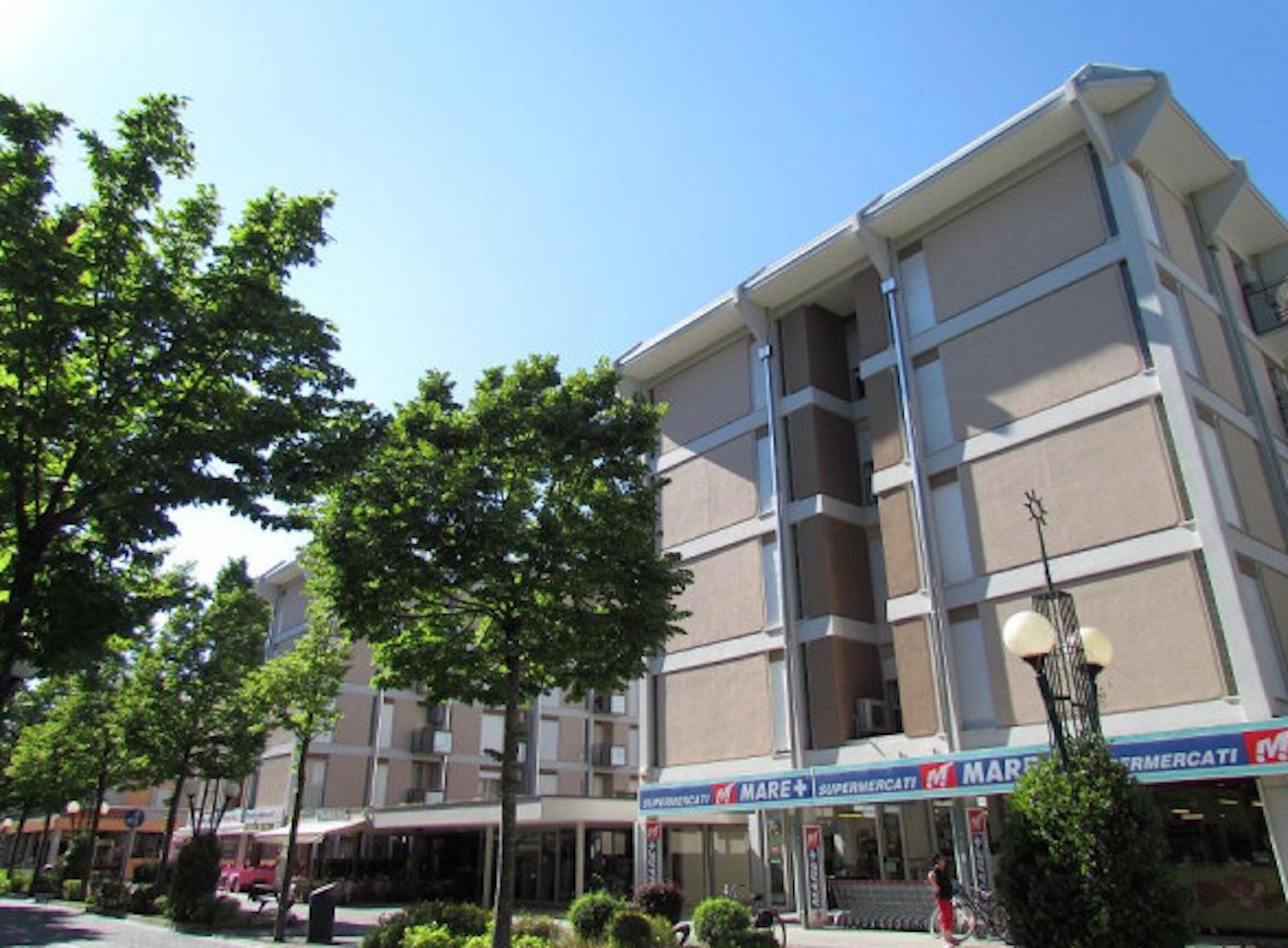 A multi-story building with a flat facade, large windows, and a ground-level storefront with signage.
