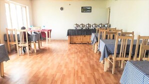 Un comedor con mesas y sillas de madera, una mesa de buffet también de madera, y un mantel a cuadros.