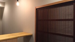 A room with a wooden partition, a light fixture, and a wooden shelf. - bnb+ Asakusa Kuramae - Hostel (Tokyo)