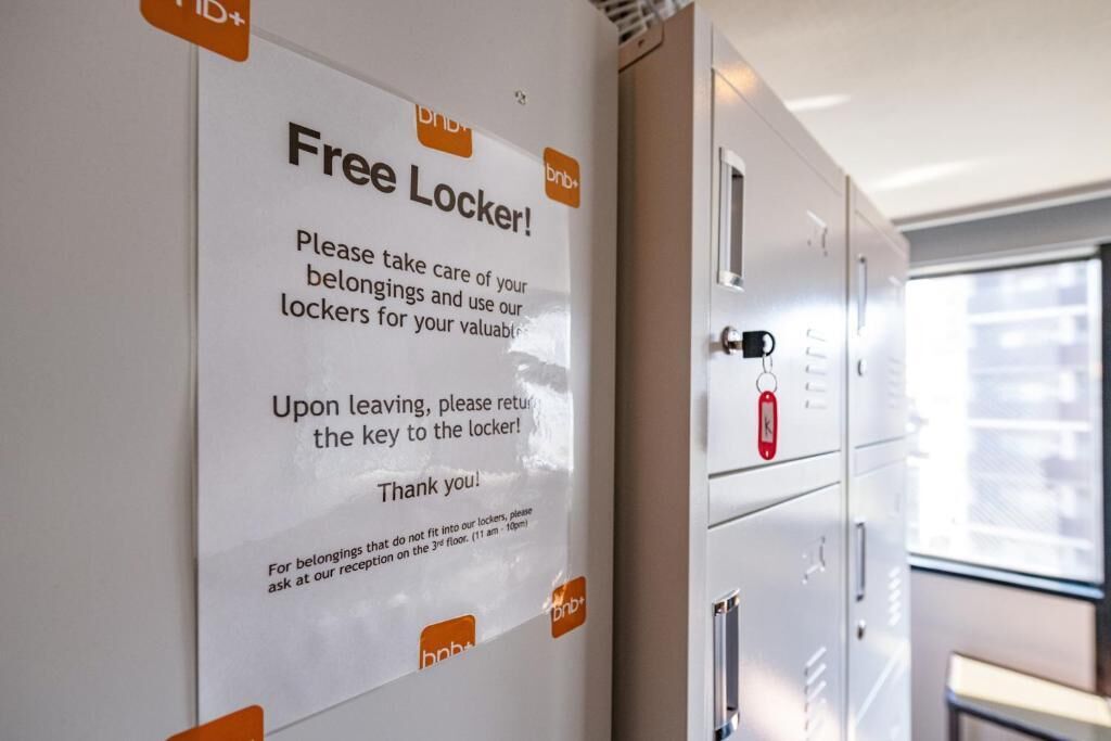 A wall with a sign instructing to take care of belongings and use lockers, and a row of metal lockers with keys.