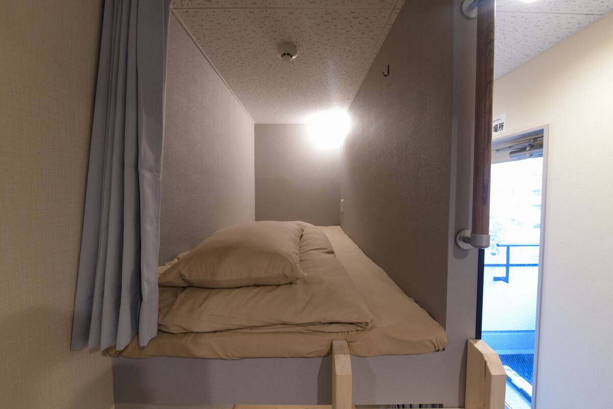 Une petite pièce avec un lit, une porte et un luminaire au plafond.