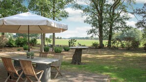 An outdoor patio with a table and chairs, a small round table with a bottle, and a canopy. - Amazing home in Hoge Hexel with WiFi (Hoge Hexel)