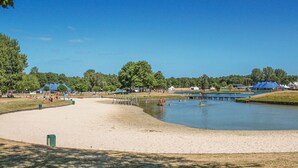 A sandy beach area with a calm lake, surrounded by trees and tents. - Amazing home in Hoge Hexel with WiFi (Hoge Hexel)