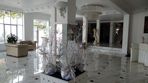 A spacious lobby with marble flooring, white furniture, and decorative elements like a large planter with white branches and a chandelier. - Cinnamon Villa Negombo (Negombo)
