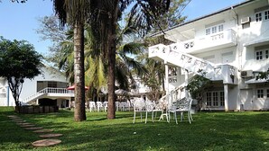 A white building with a staircase, surrounded by palm trees and a grassy area with white chairs. - Cinnamon Villa Negombo (Negombo)