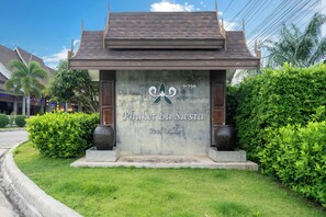 A sign for Phuket La Siesta Pool Villa with a traditional roof and a large decorative vase. - Phuket La Siesta, Naiharn Beach (Rawai)