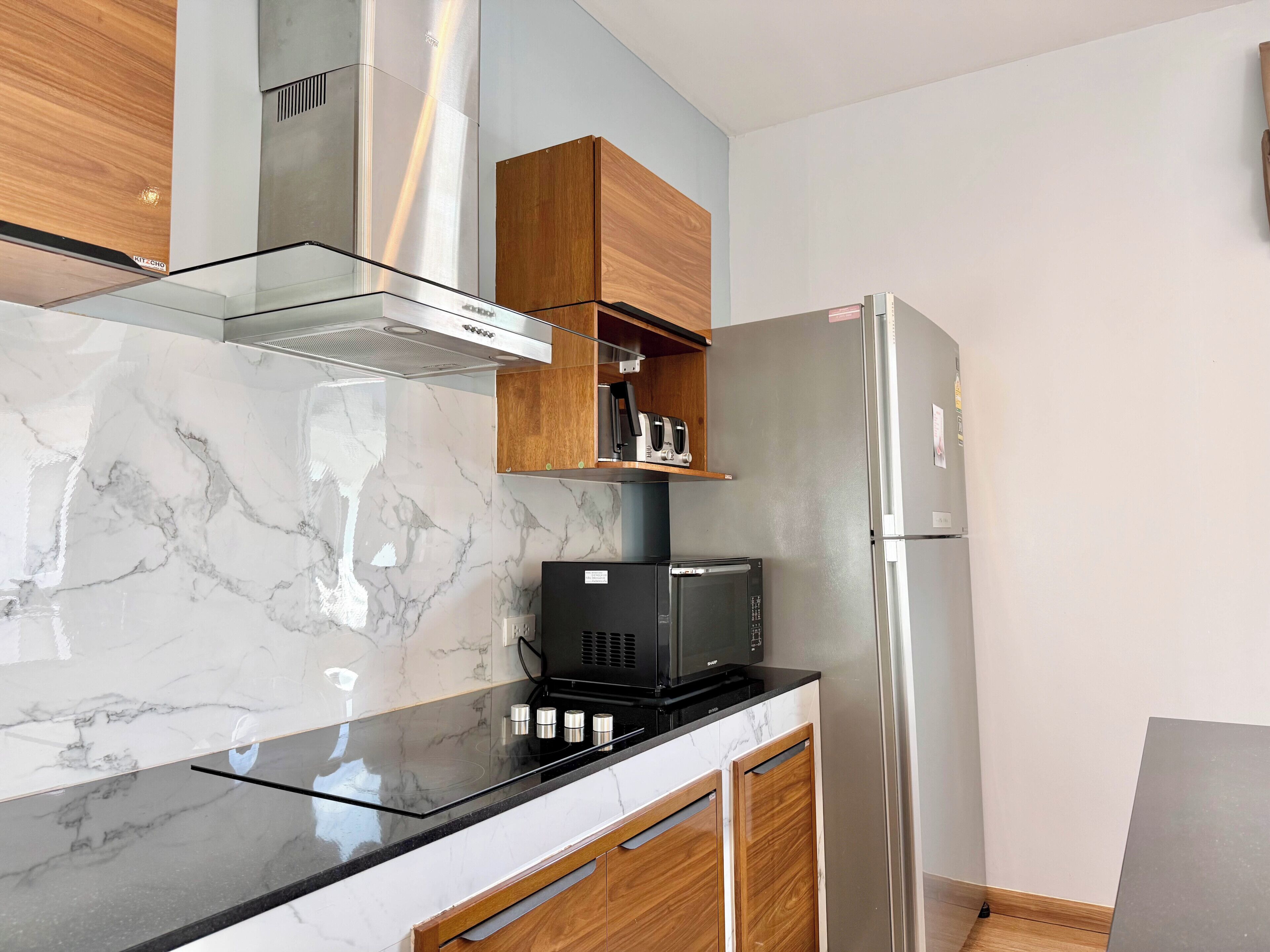 A modern kitchen with a marble countertop, stainless steel appliances, and wooden cabinetry.