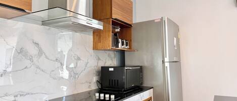 A modern kitchen with a marble countertop, stainless steel appliances, and wooden cabinetry.