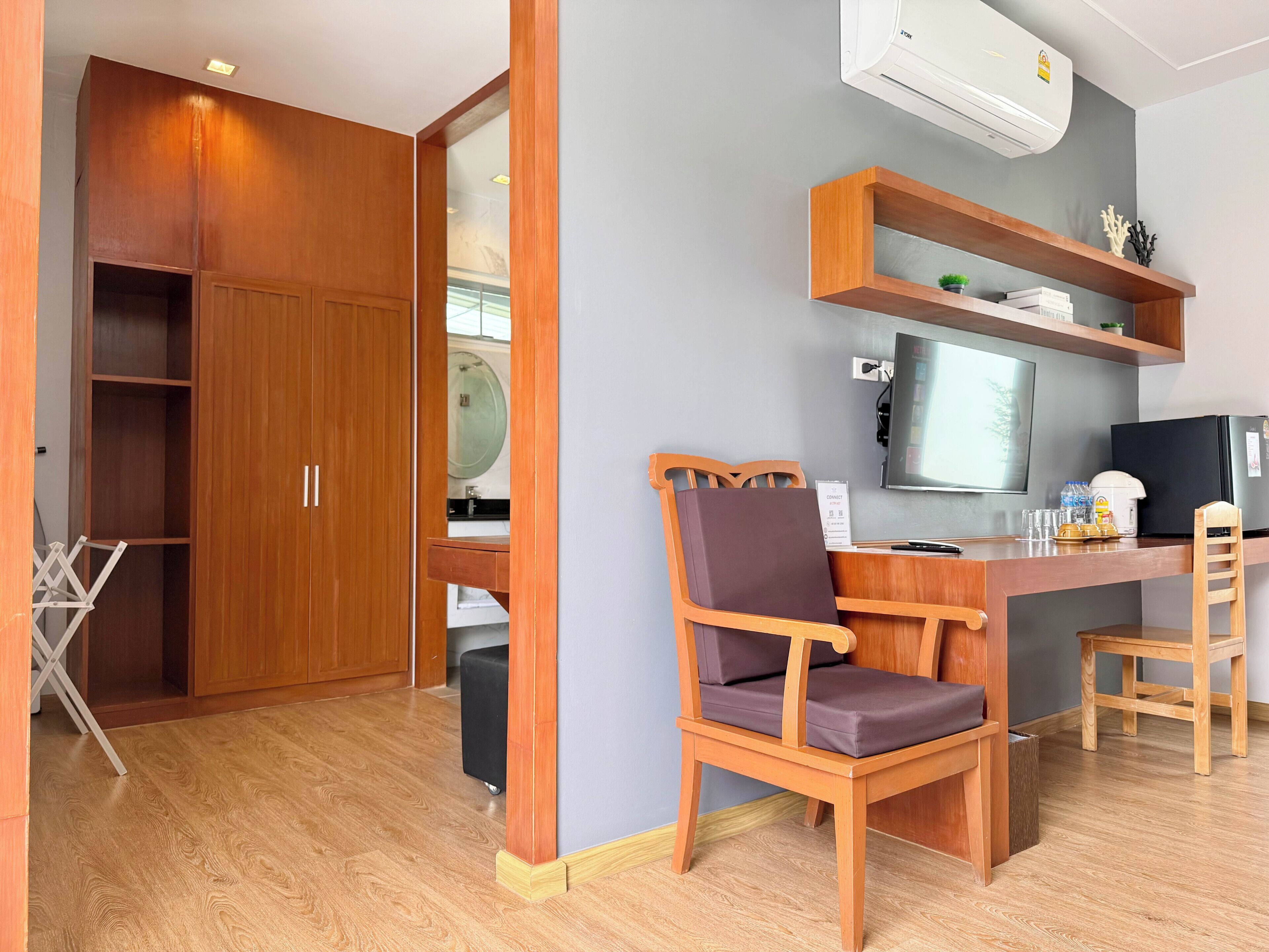 Une pièce comprenant un bureau en bois, une chaise, un téléviseur et une armoire.