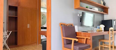 Une pièce comprenant un bureau en bois, une chaise, un téléviseur et une armoire.