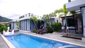 Una piscina al aire libre, sillones reclinables de piscina