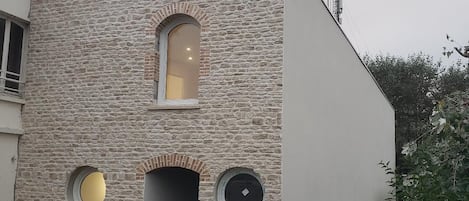 Um edifício moderno com fachada de pedra, uma janela pequena e uma janela circular.
