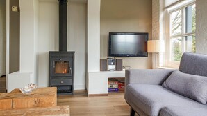 Een woonkamer met een open haard, een televisie en een bank.